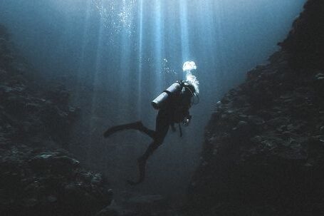 Scuba Tank - Scuba diver swimming near rocks